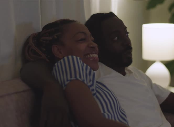 A man and woman cuddle up together on the couch