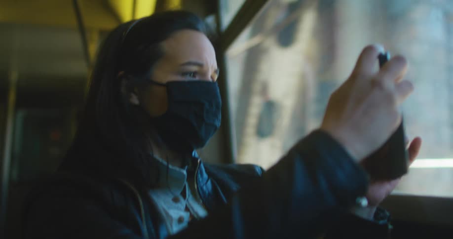 Woman wearing a face mask takes pictures of the city from the train