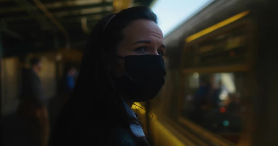 Woman wearing a black face mask waiting for the train at the station
