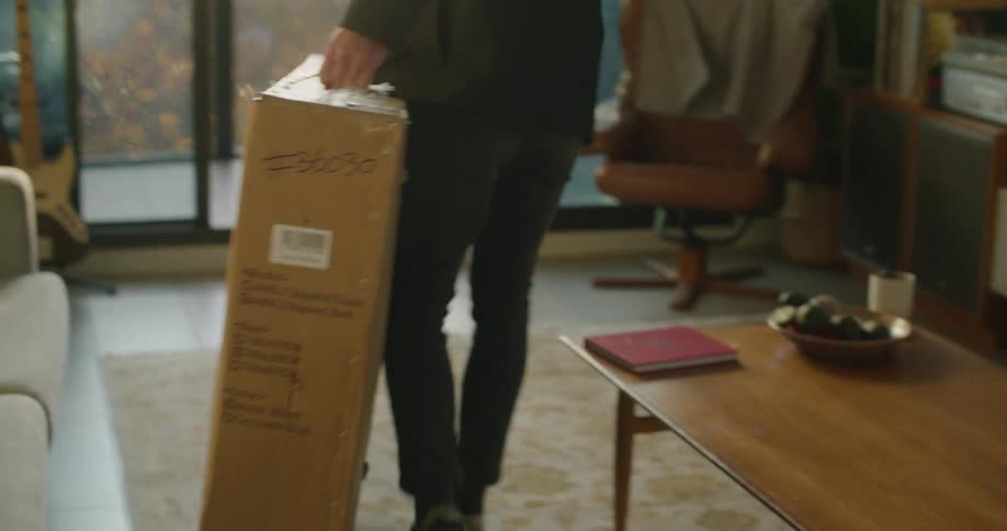 A man carrying a large cardboard box into a living room at home