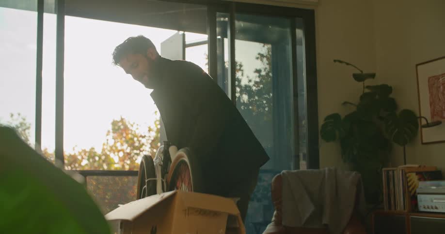 A man at home takes a bicycle out of a box