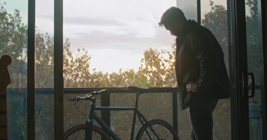 A man that is putting a bicycle on a balcony