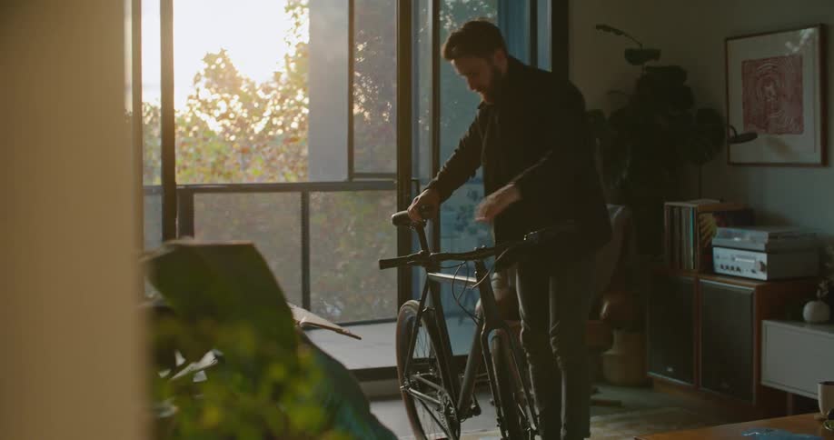 Man finishes assembling a bicycle on the living room at sunset