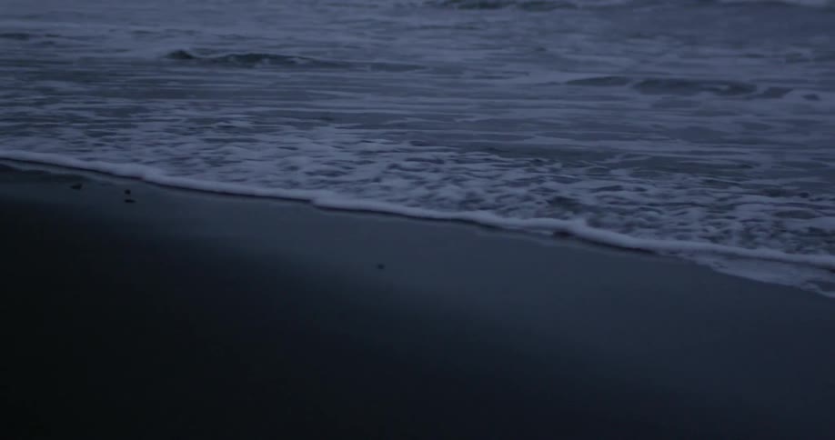 Waves gently wash onto a beach at dusk