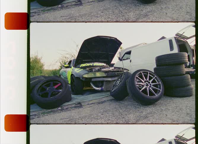 A film strip of piles of tires next to a race car with an open hood