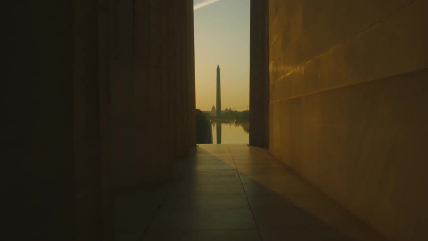 The tall washington monument stands tall before a beautiful sky as the sun rises