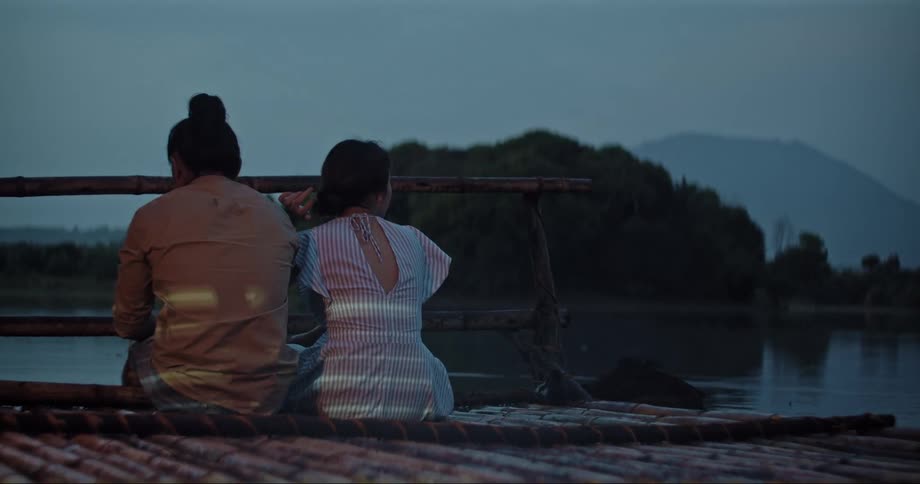 Man and Woman sitting on the pier of a lake