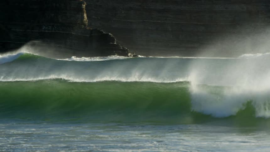 Rough water and waves are splashing as they roll in
