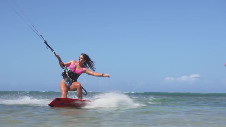 A woman kiteboarding in blue water