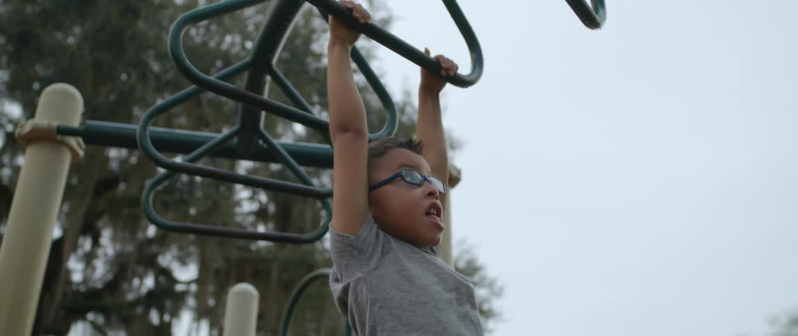 A young boy goes across the monkey bars at a playground