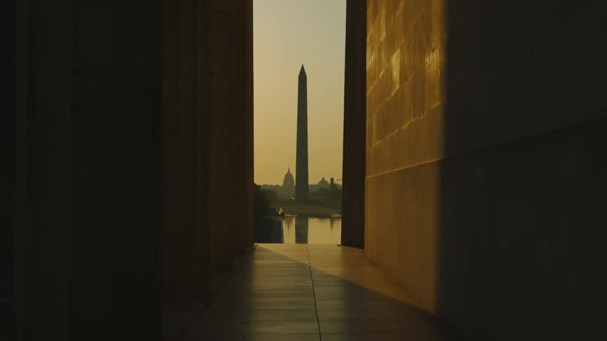 A building with a wall and pillars with the lincoln memorial the sky and clouds in the background