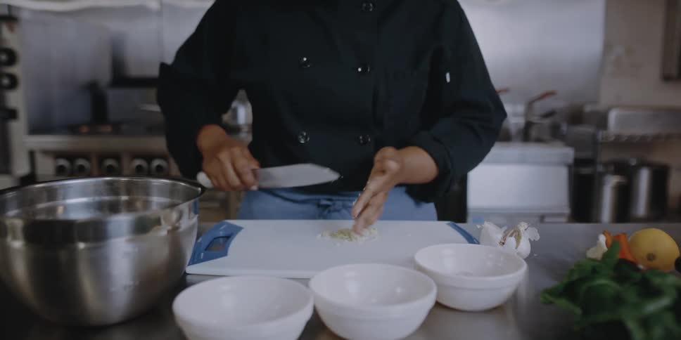 Female chef slicing vegetables on the kitchen of a restaurant