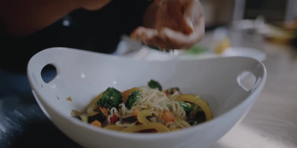 A woman squeezes lemon over a bowl of food