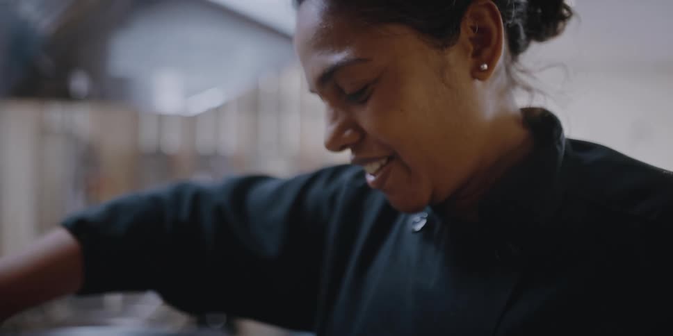 Female chef cooking vegetables on a pan in the kitchen of a restaurant