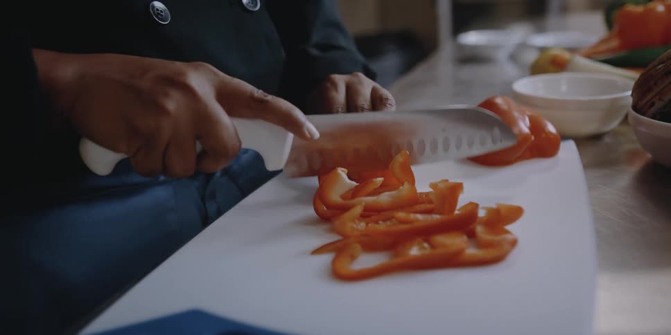 A chef slices red peppers on a cutting board