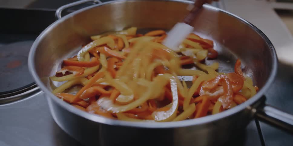 Female chef cooking vegetables on a pan in the kitchen of a restaurant