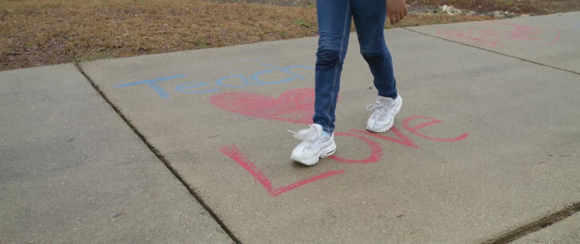 Girl draws message on sidewalk about teaching love