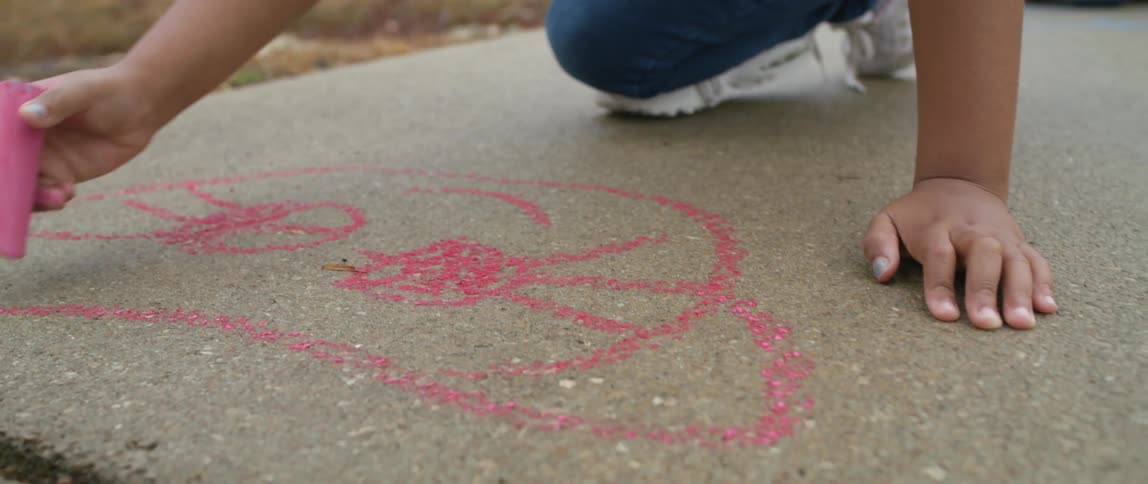 A child drawing with sidewalk chalk outdoors