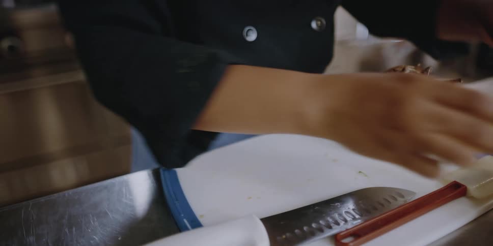 A chef cuts a lemon in half on a cutting board then brings over two small bowls