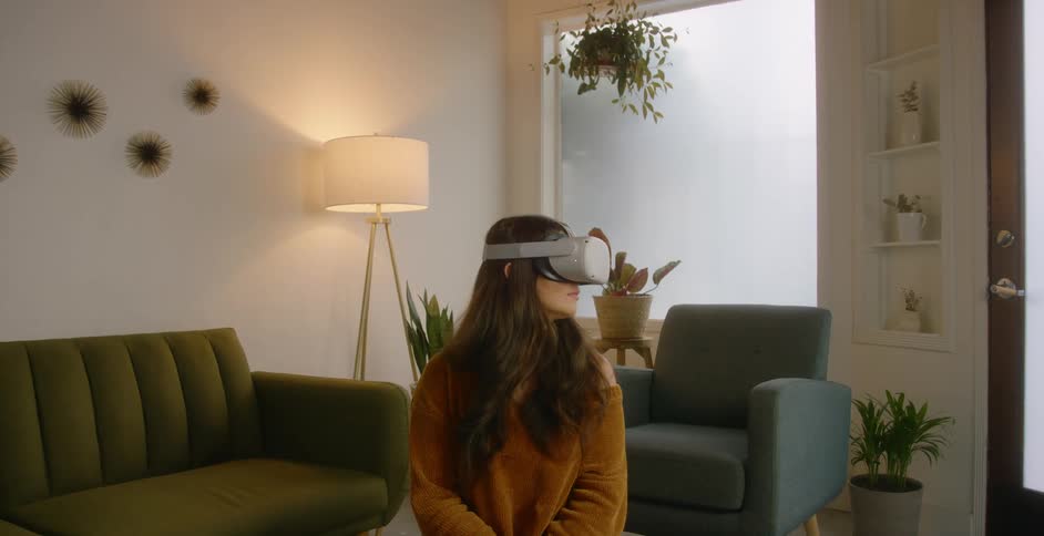 A woman is using a virtual reality headset n her living room