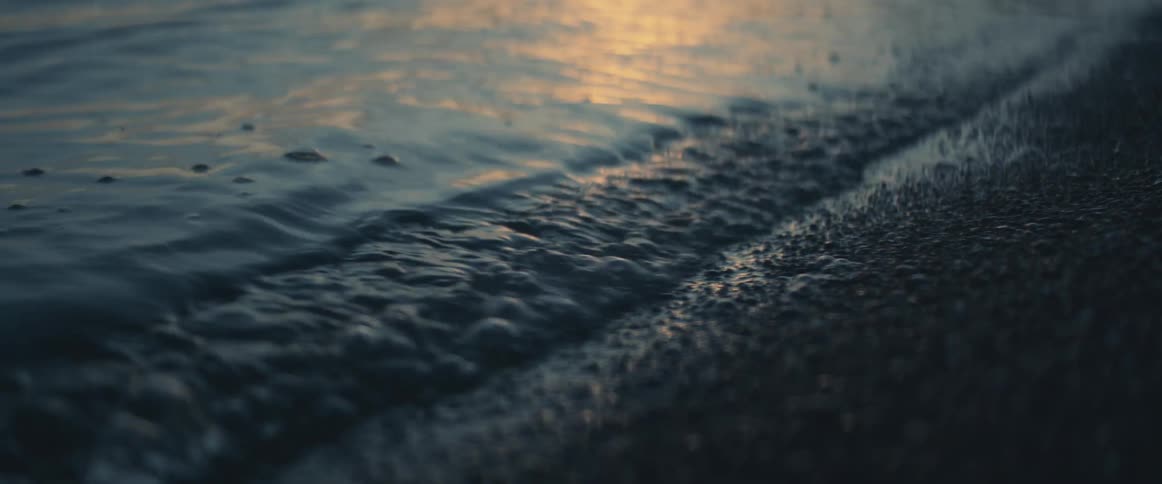Small waves wasing over the sand on the beach shoreline at sunset