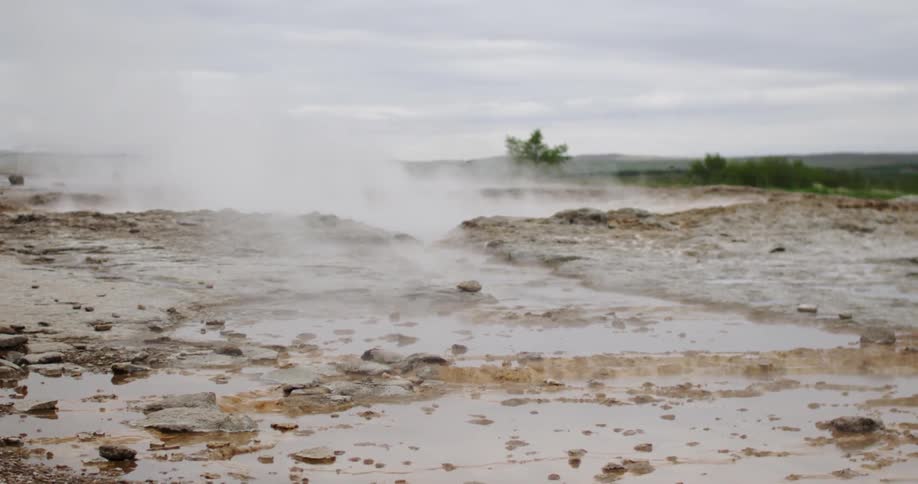 A rocky area has steam rising from the surface