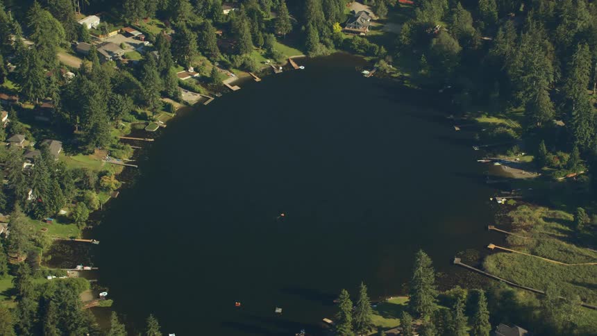 Aerial shot of a lake which is surrounded by houses and trees