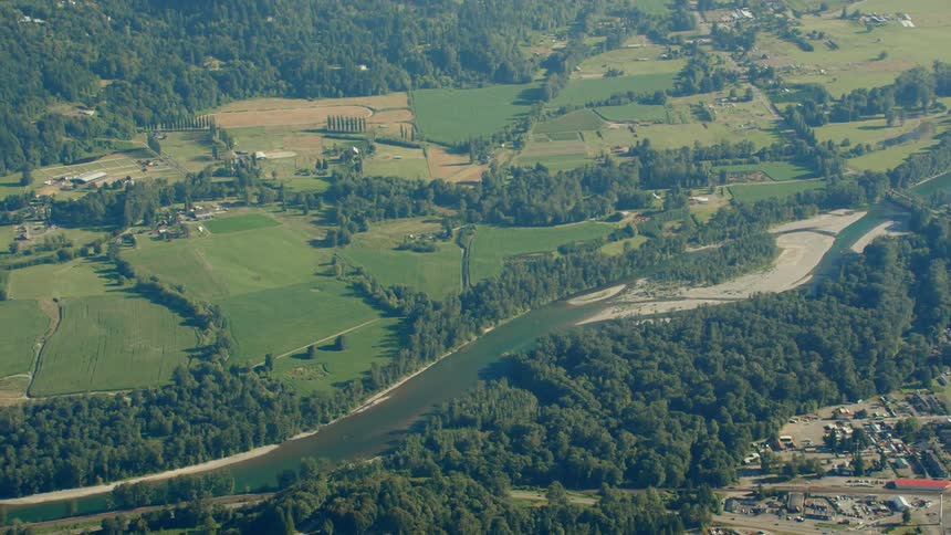 An aerial view of a river flowing through rural fields on a summer day