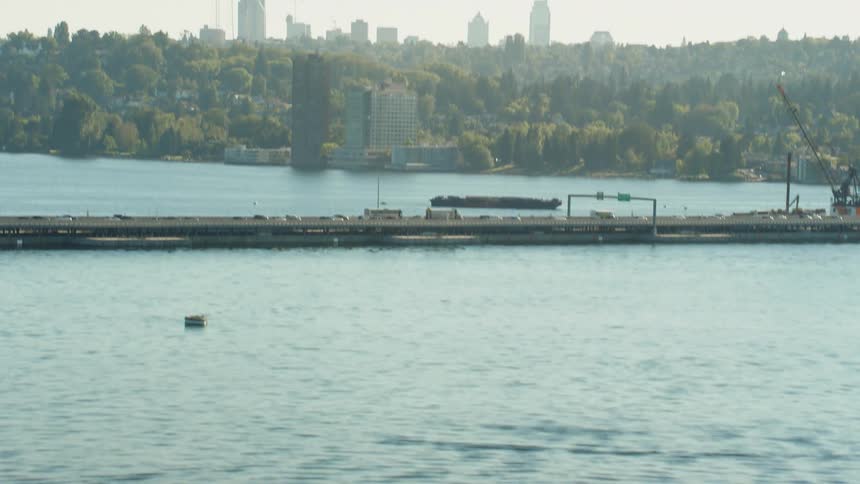 Heavy traffic passes on a bridge that leads to a dense downtown city