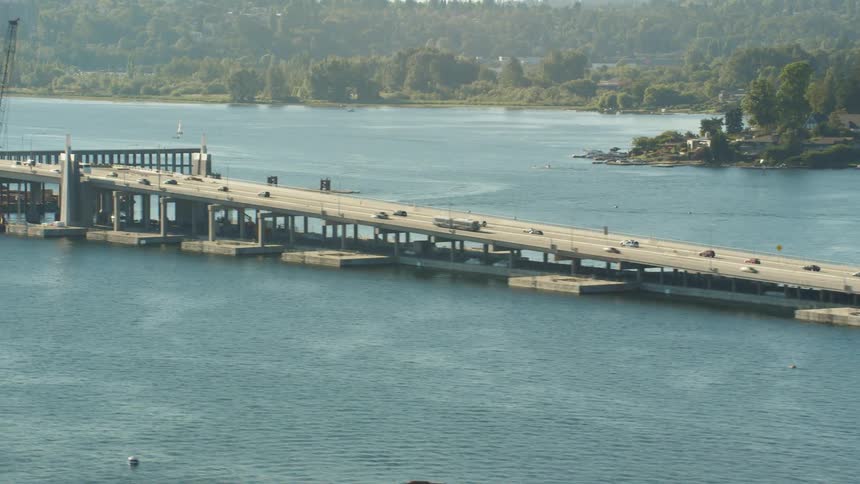 An aerial view of boats in the water and cars driving across a bridge