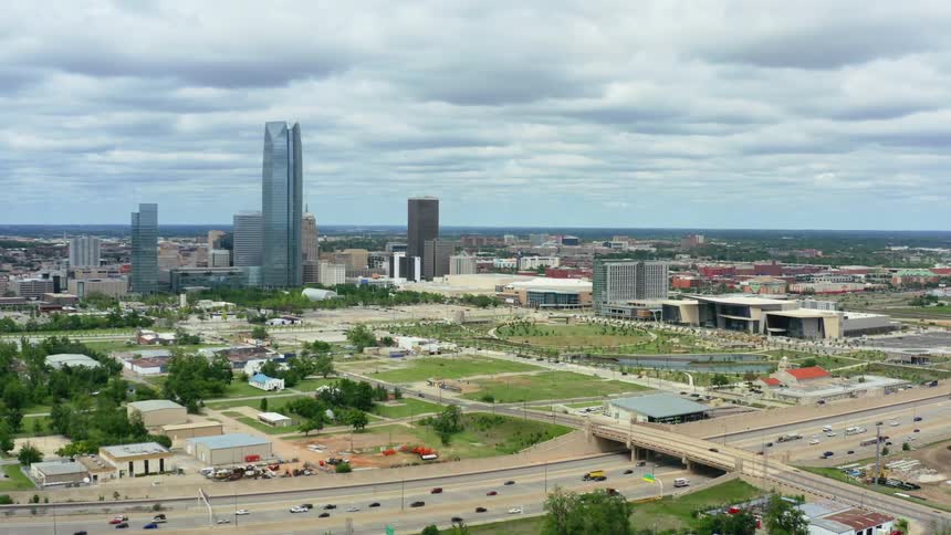A city with buildings and trees with the sky and clouds in the background