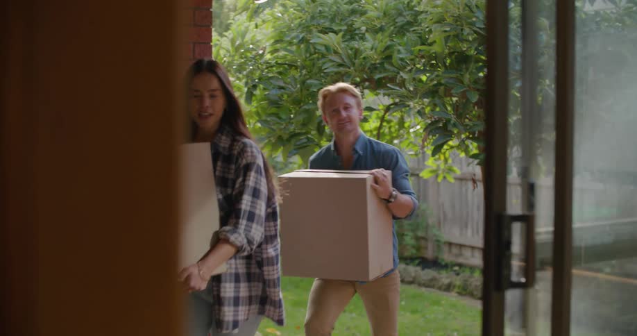 Couple moving cardboard boxes inside the house at daytime
