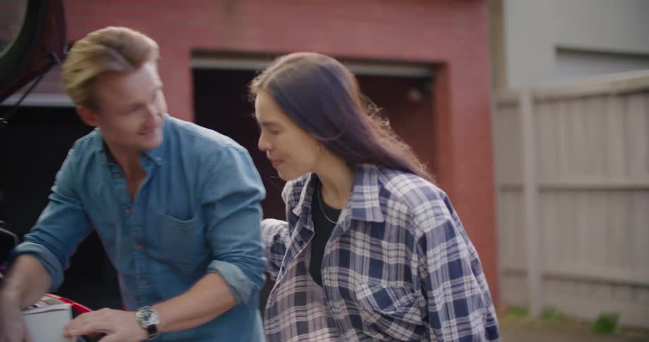 A man and young woman talking next to the open door of a car