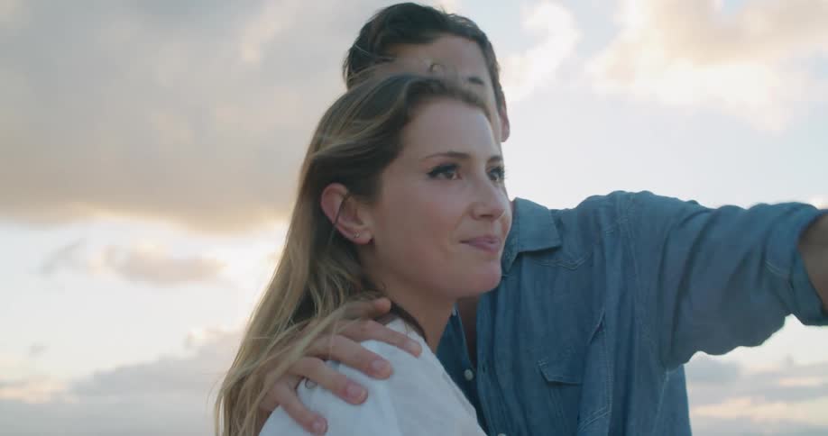 Young couple talking and hugging on the beach at sunset