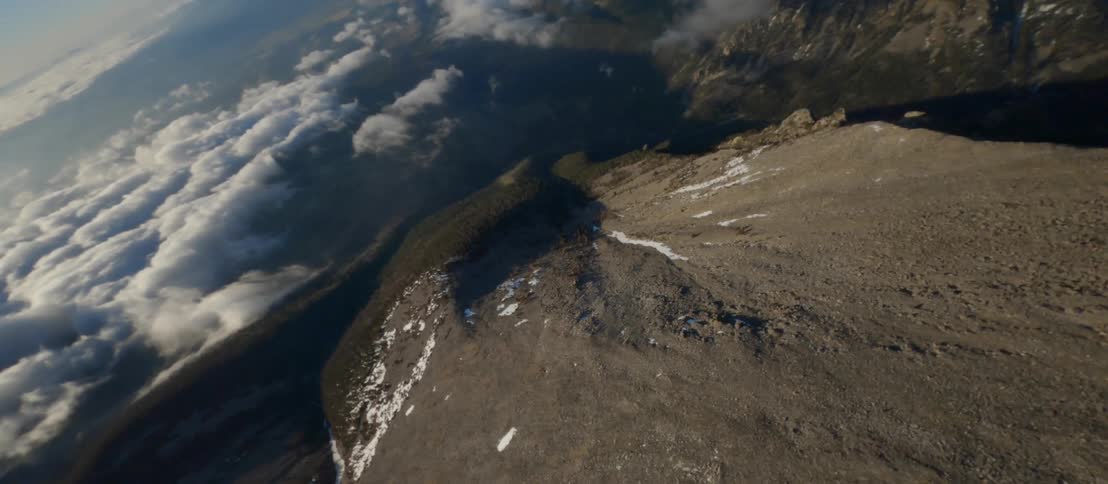 A rocky mountain towers high above a dense layer of clouds
