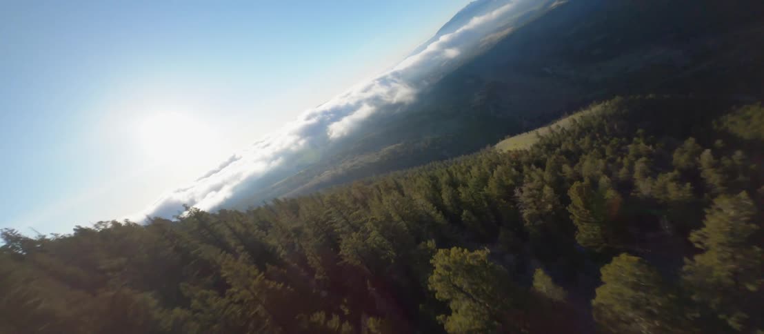 A mountain range with trees with the sky and clouds in the background