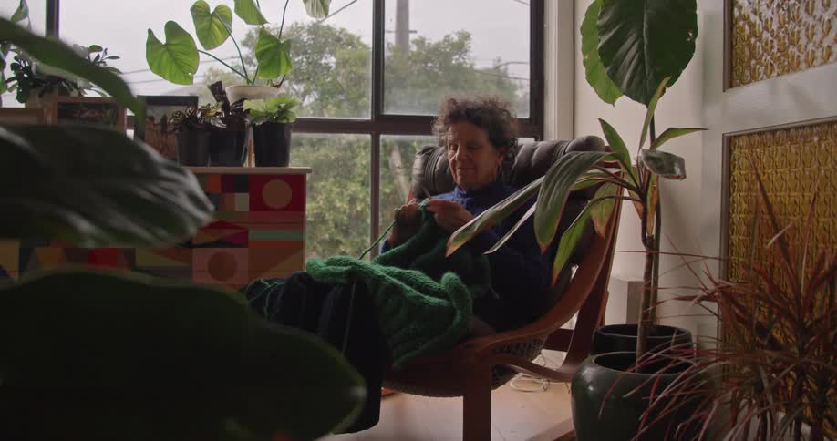 A woman sitting in a chair knitting indoors