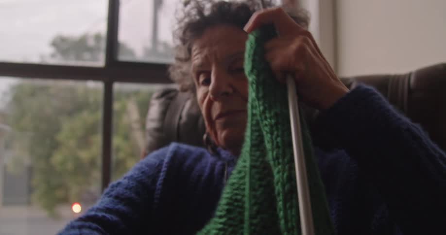 Grandmother sitting on a couch at home kniting