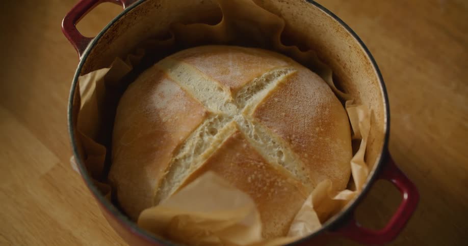 A person sets down a pot containing a freshly baked round of bread
