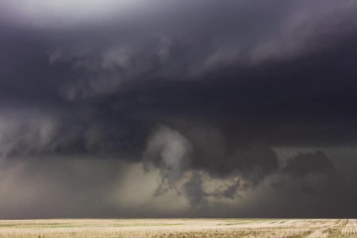 Roiling black storm front flows across fields