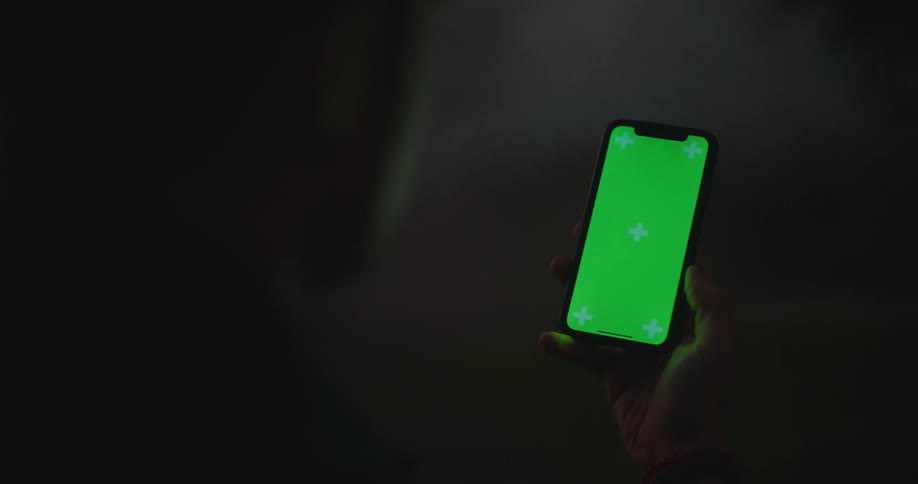 A person looking at a glowing smartphone in the dark