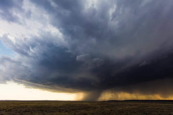 Dark clouds form over a rural field as a storm comes through
