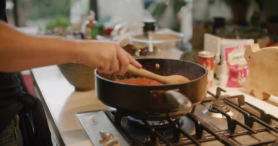 A man cooking as another man sits in the background