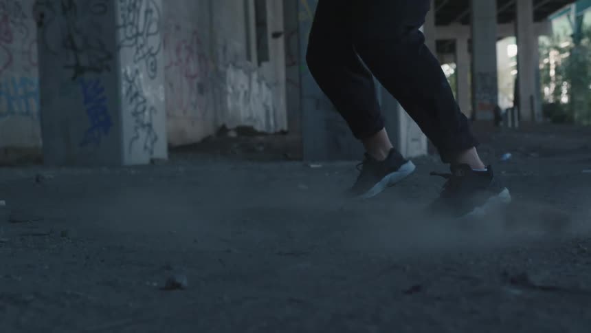 A woman is dancing under the underpass