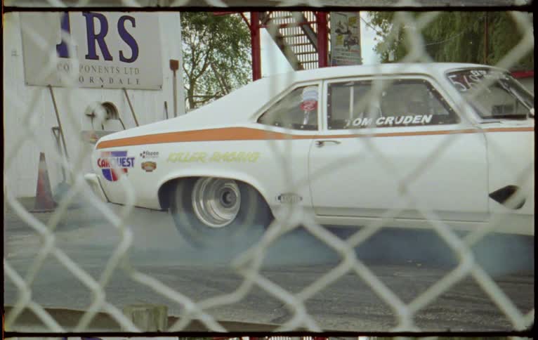 Smoke comes off a race cars tires as the wheels spin and then the car takes off