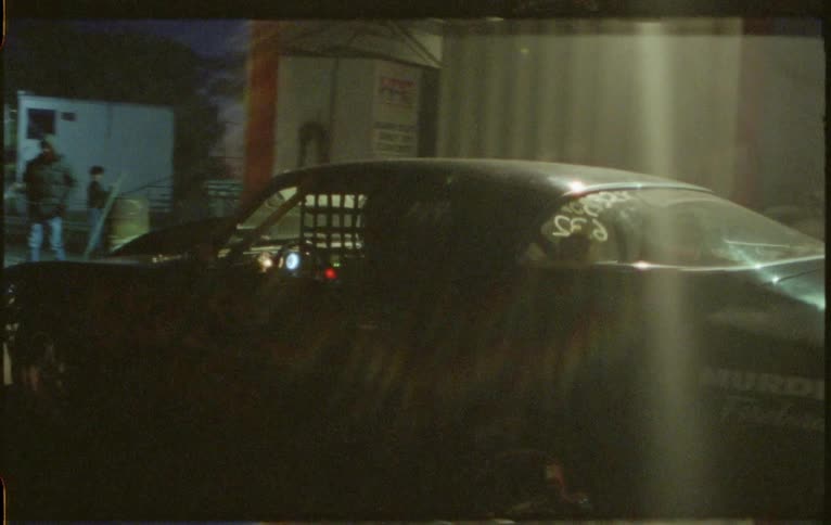 A racing car with bright headlights driving outside at night
