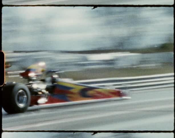 Two vehicles drag racing on a track with trees the sky and clouds in the background