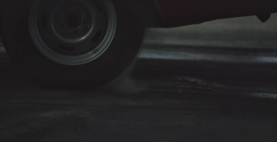 A sports car accelerates quickly with its breaks applied so its rear wheel spins beneath it
