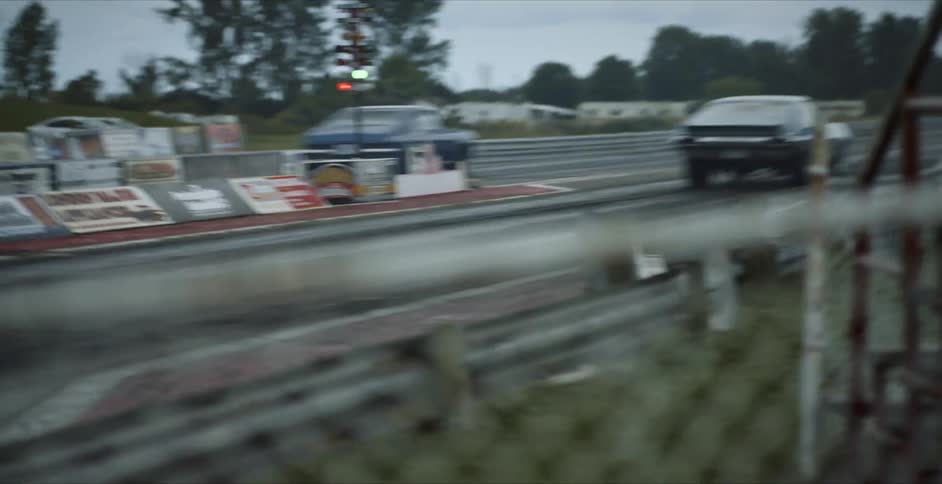 Two car race each other on a race car track outside