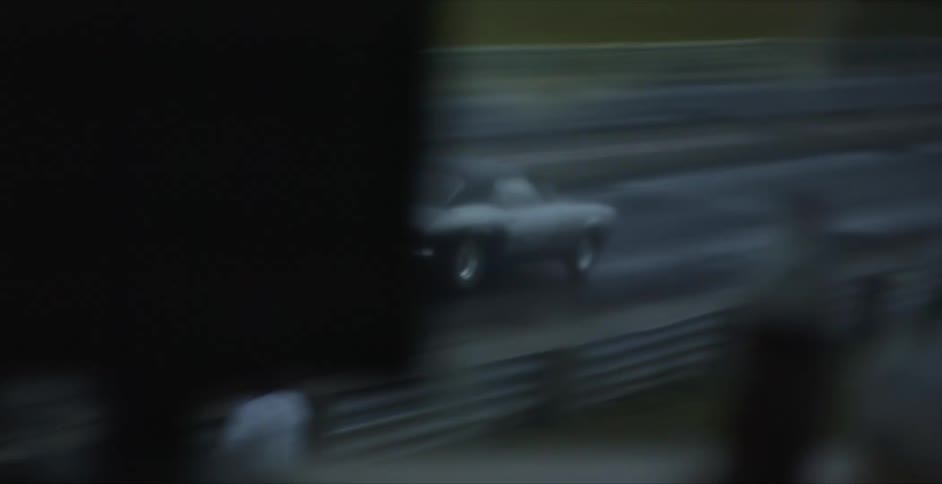 Two vehicles drag racing on a track with trees the sky and clouds in the background